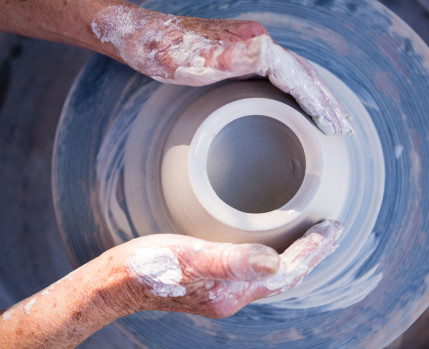 mãos a modelar barro numa roda de oleiro