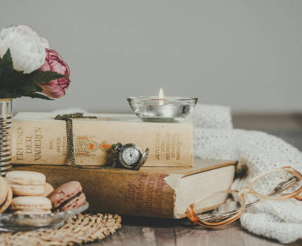 mesa com flores, livros, chávena de chá e macarons