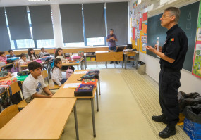 homem fardado a falar para estudantes