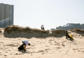 duas pessoas a limpar uma praia 