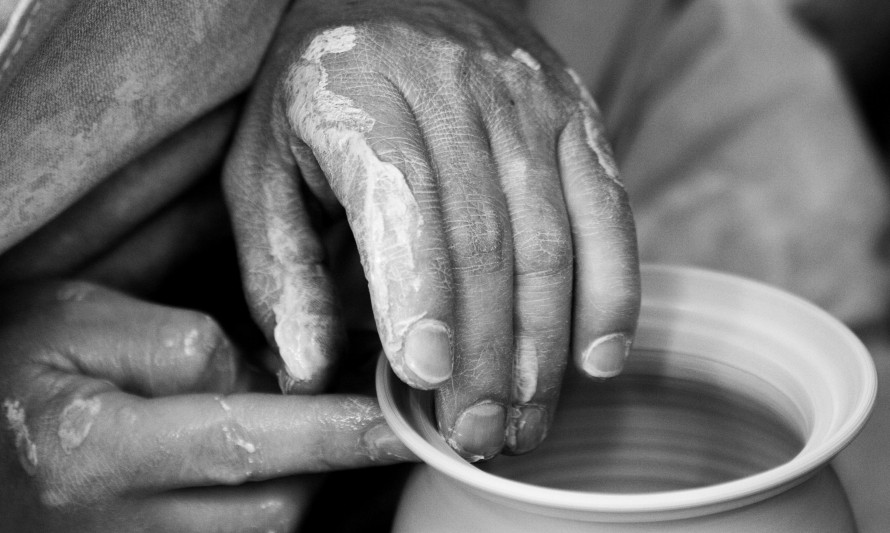 Mãos a esculpir barro numa roda de oleiro
