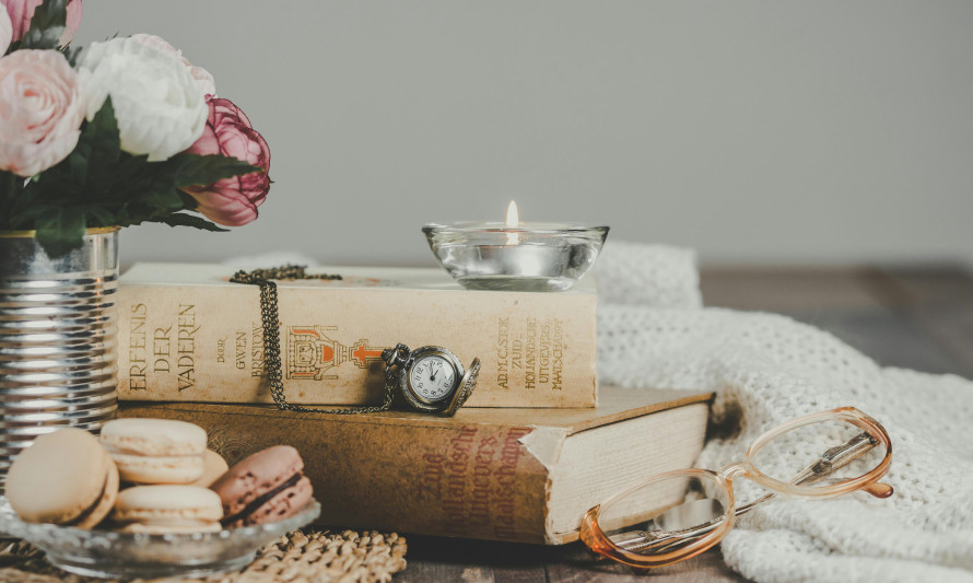 mesa com flores, livros, chávena de chá e macarons