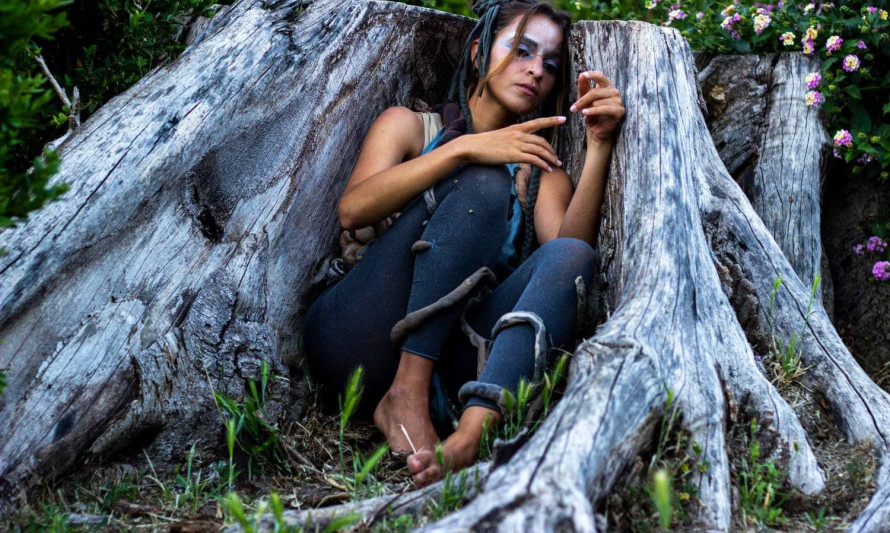 Mulher acocorada entre as raízes de uma árvore