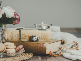 mesa com flores, livros, chávena de chá e macarons
