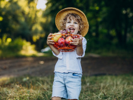 Criança com uma cesta de fruta nas mãos
