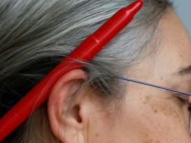 Foto de rosto com caneta vermelha atrás da orelha