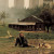 Imagem do filme "Nostalgia" - um homem e um cão sentados na relva em frente a uma casa