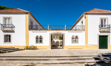 Fotografia da fachada principal da Casa da Cerca com os portões abertos